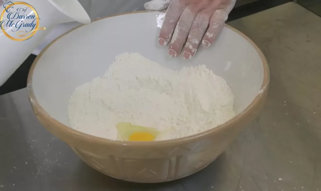 於麵粉碎中央開洞，加入蛋液及分次加入 ¾ 杯奶